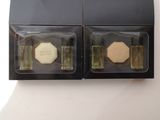 two bottles of perfume in a black box on a white surface