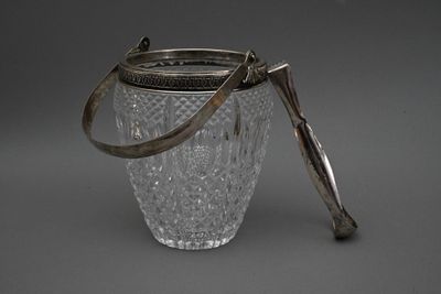 un bocal en verre muni d'une poignée en métal posé sur une surface grise
