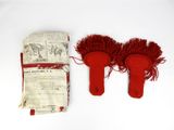 pair of red slippers with red fringes on a white surface