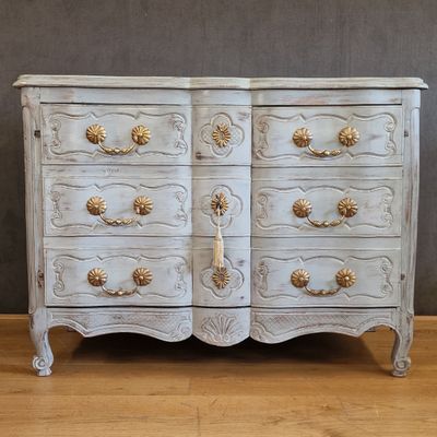a white chest of drawers with gold handles on it