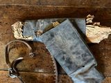 une vieille paire de chaussures et un sac posés sur un parquet