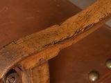 a close up of a leather chair with a wooden arm