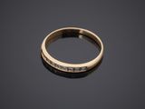 a yellow gold ring with diamonds on a black surface
