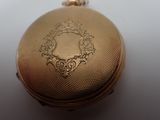 a gold pocket watch on a white surface