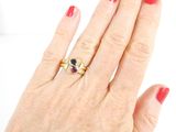 a woman ' s hand with a red manicure and a gold ring on it