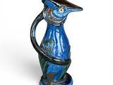 un vase bleu orné d'un oiseau, posé sur un fond blanc