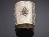 an antique silver bracelet with a red stone in the center