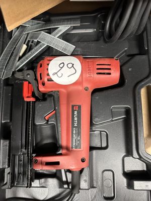 une perceuse filaire rouge dans une boîte avec d'autres outils