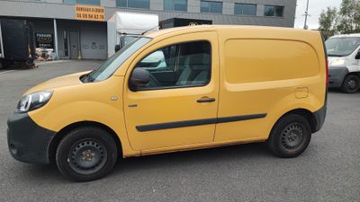 La camionnette jaune est garée sur le parking devant l'immeuble.