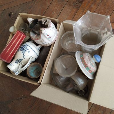 une boîte en carton remplie d'objets divers posée sur un plancher en bois