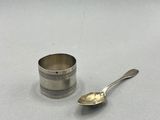 une tasse et une cuillère plaquées argent posées sur une surface blanche