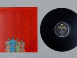 a black vinyl record sitting on top of a table next to a red album