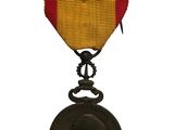 une vieille médaille ornée d'un ruban rouge et jaune sur fond blanc