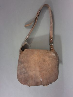 sac à main en cuir beige muni d'une bandoulière, posé sur une surface blanche, sur fond blanc