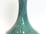 a green vase that is sitting on a white surface