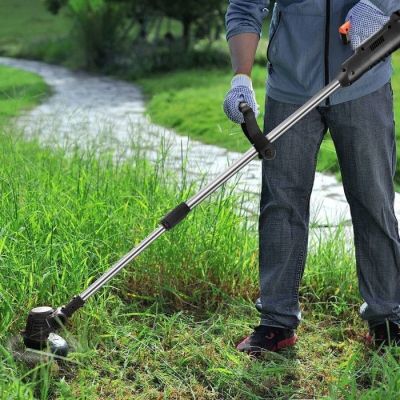 Cet homme utilise une débroussailleuse pour tondre l'herbe.