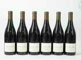six bouteilles de vin sont alignées sur une surface blanche