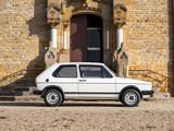 a small white car parked in front of a stone building