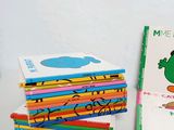 a stack of children ' s books on a table next to a stack of pencils