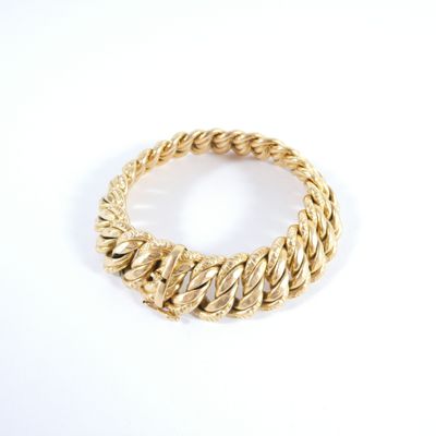 an image of a close up of a gold bracelet on a white surface