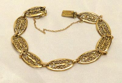 une photo d'un bracelet en or posé sur un tissu blanc