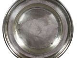 assiette en argent posée sur un support, sur fond blanc, avec un fond blanc