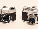 two cameras sitting next to each other on a white surface