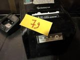 une petite boîte noire sur laquelle est accrochée une étiquette jaune