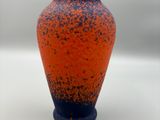 an orange and blue vase sitting on a white surface