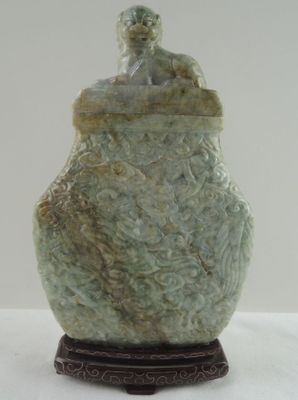 une statue représentant un homme assis sur un vase