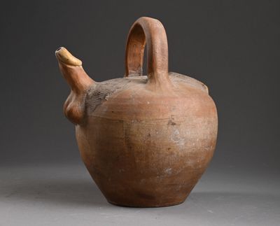 un vase marron muni d'une anse, posé sur un fond gris