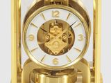 une horloge en or posée sur une surface blanche
