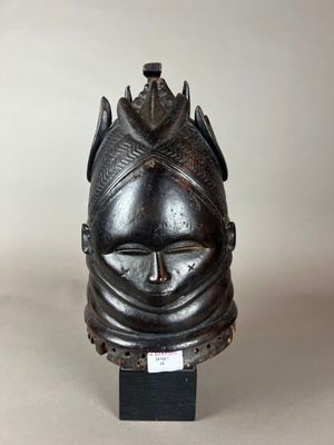 un gros plan d'un masque noir posé sur un support, sur fond blanc