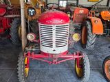 a red tractor sitting in a garage next to other tractors