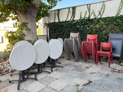 many chairs and tables that are outside by a tree