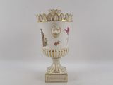 a white vase with a gold decoration on it