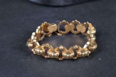 gros plan d'un bracelet en or sur une surface noire