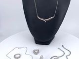 necklaces, bracelets, and rings on display on a white table