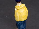 a small figurine of a man in a yellow shirt and blue pants
