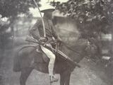 a black and white photo of a man on a horse with a rifle