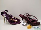pair of purple high heeled shoes with gold accents on a white surface