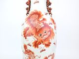 un vase blanc orné de fleurs orange sur fond blanc