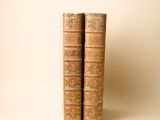 deux vieux livres sont empilés l'un sur l'autre sur une surface blanche