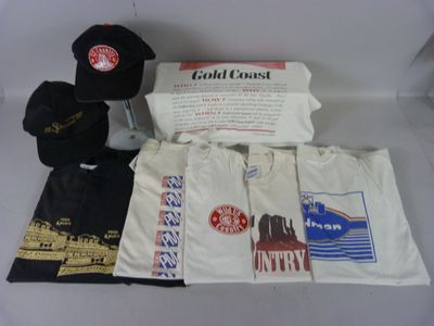 Plusieurs t-shirts, casquettes et autres articles sont disposés sur une table