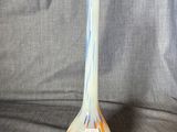 an orange and blue vase sitting on top of a gray cloth