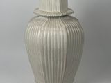 un vase blanc muni d'un couvercle, posé sur une table