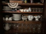 many plates and glasses on the shelves in the cabinet