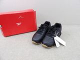 une paire de chaussures de course noires et dorées posée à côté d'une boîte à chaussures rouge