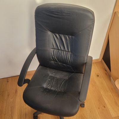 a black office chair that is on a wooden floor
