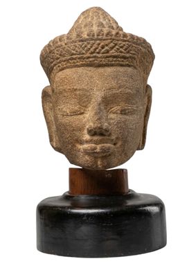 un gros plan d'une statue représentant une tête posée sur un socle en bois